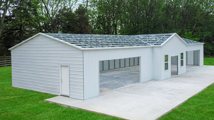 Large white metal barndominium with attached two-car garage and pond view